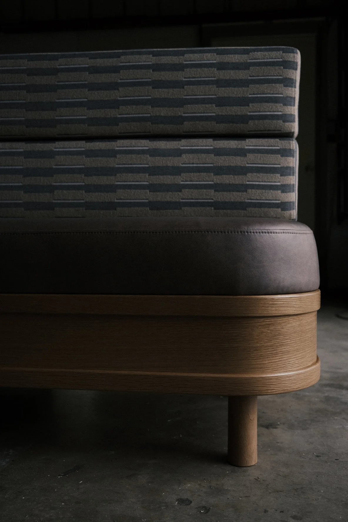 Curved banquette with dark upholstered seat on a radiused white oak base for Little While, San Diego