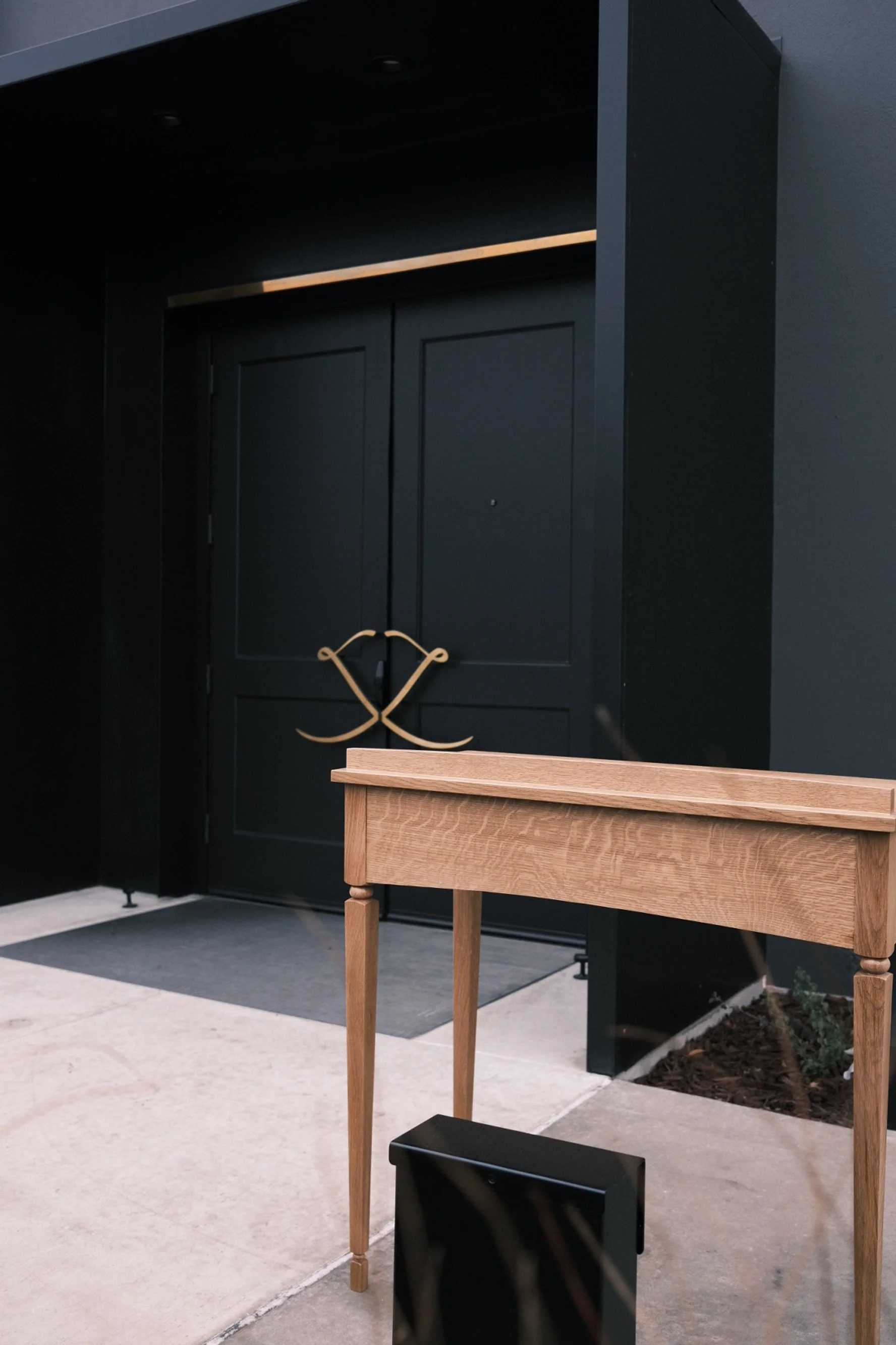 White oak console table with turned legs beside black double doors at The Kitchen, Sacramento