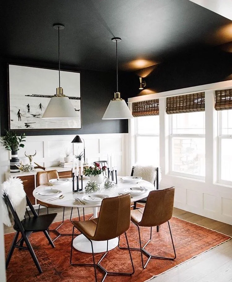 1. Wall Color Painting your entire room black creates a bold dramatic look that we're all for. But if you don't feel comfortable committing to that much black, consider painting just your ceiling and upper part of your walls. Pair it with white wainscoting for a crisp textural layer that'll help brighten up the space. Make sure to carry white throughout the room to balance the black and white combo. Have fun with textures like they did here with the chair furs and table. Then to make sure the room doesn't feel like it's toppling over, bring white up to the top of the room like you see here with the artwork and pendant lights. Layer the room with a bold rug to give the space a pop of color. 