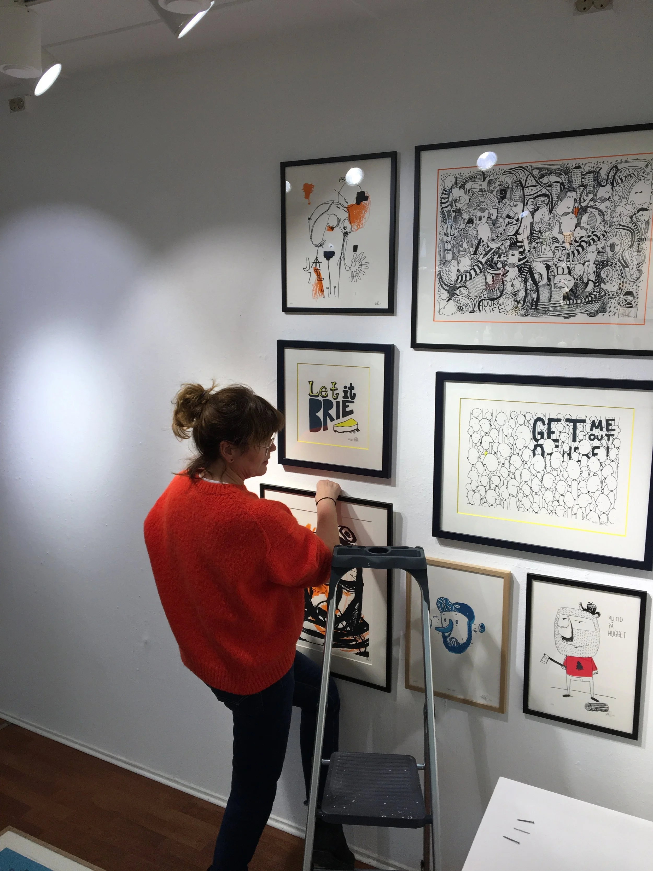 Gallerist Cathrine er hands on og henger opp silketrykkene.