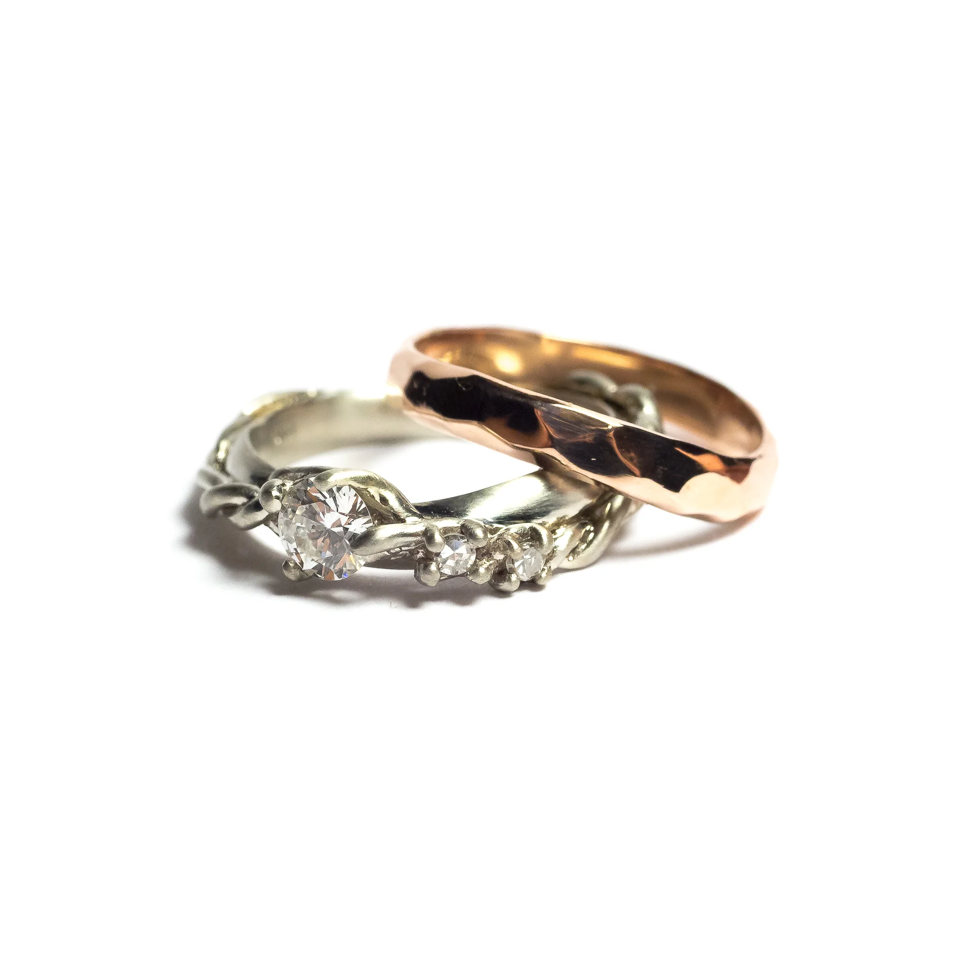 Thing ring as actually designed by my client. He provided me with sketches that I worked off of to create these pieces for him. The wedding band is hand hammer faceted 14k rose gold, and the wedding ring is a smooth half round band with twisted vines holding 3 diamonds in graduating size. The diamonds were from her grandmothers wedding set. 