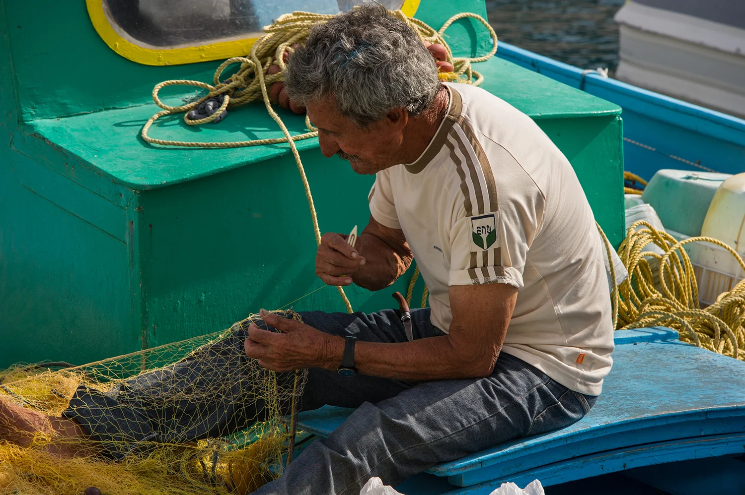 FISHERMAN REPAIRING HIS NETS