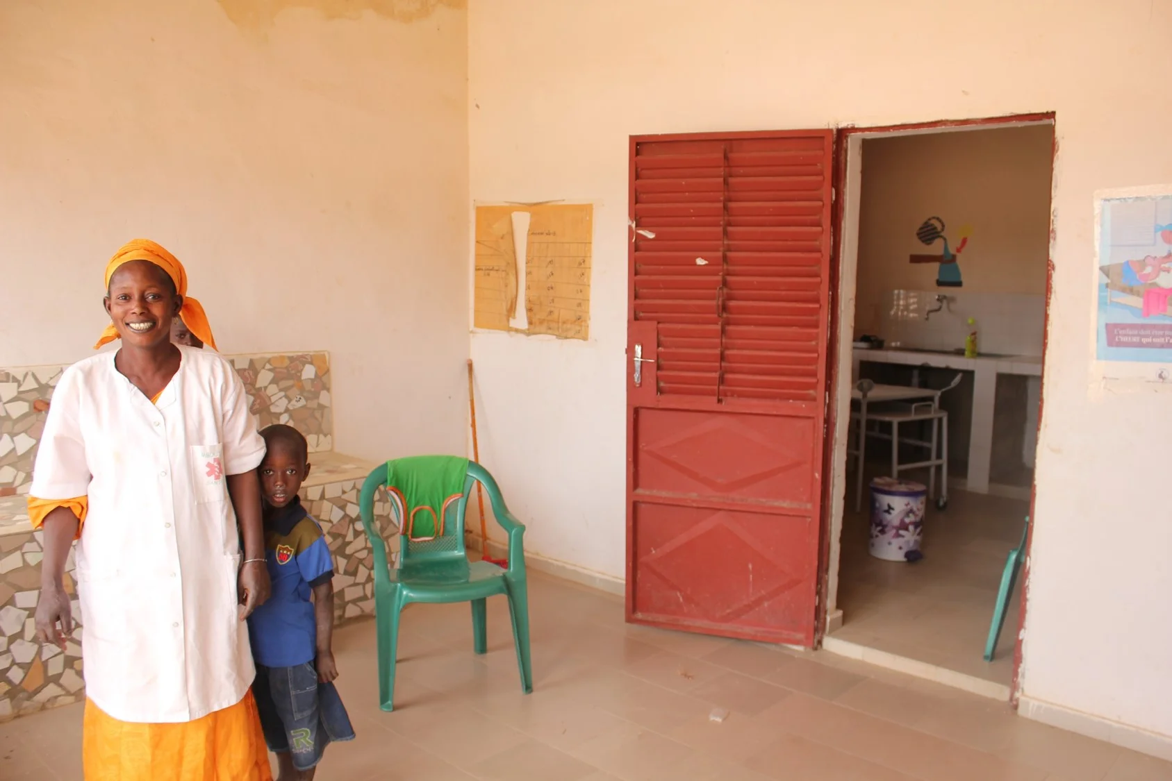A midwife proudly standing in the waiting area of a newly opened health post.