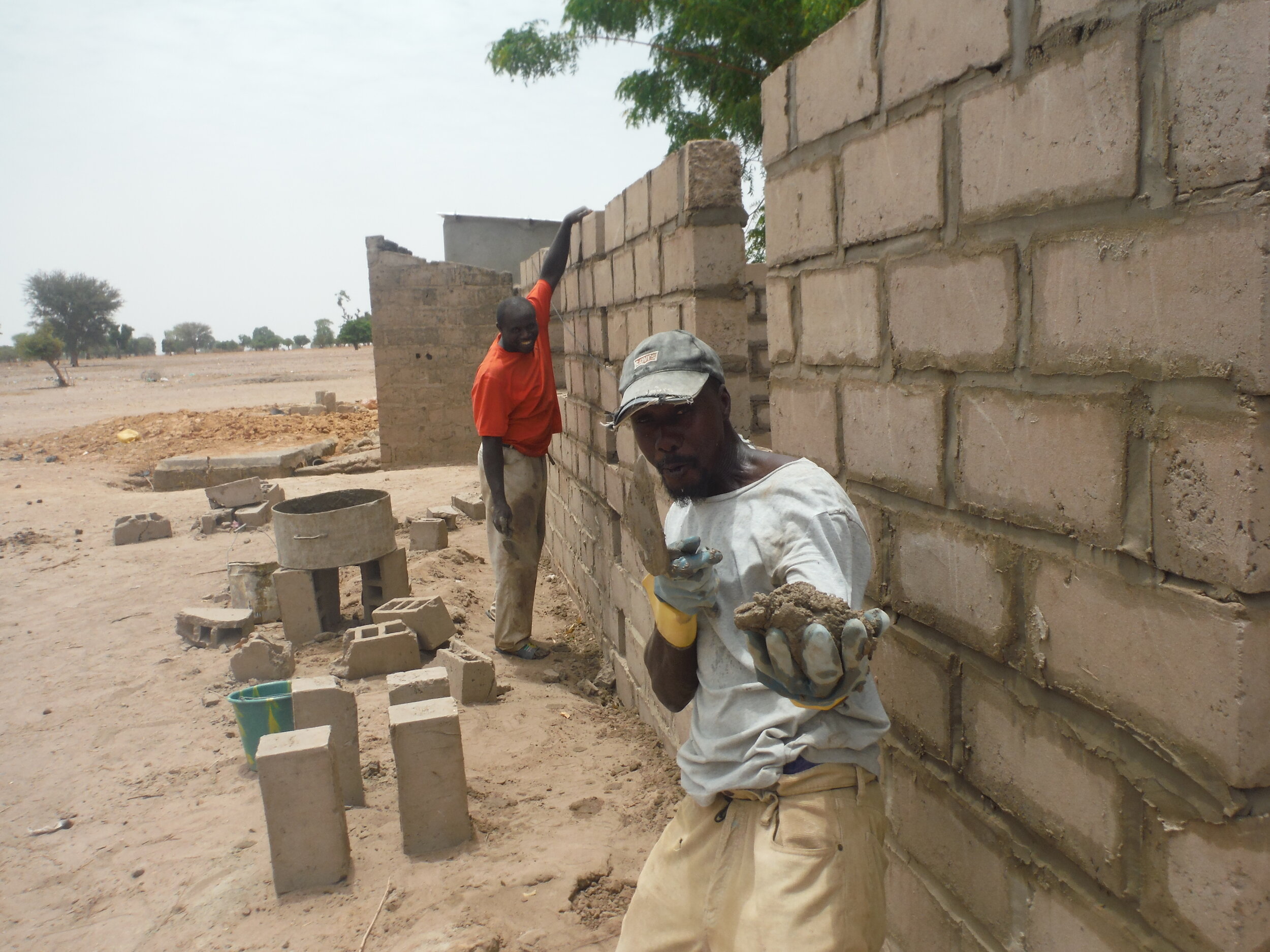 Community volunteers building walls for teacher housing adjacent to the school.