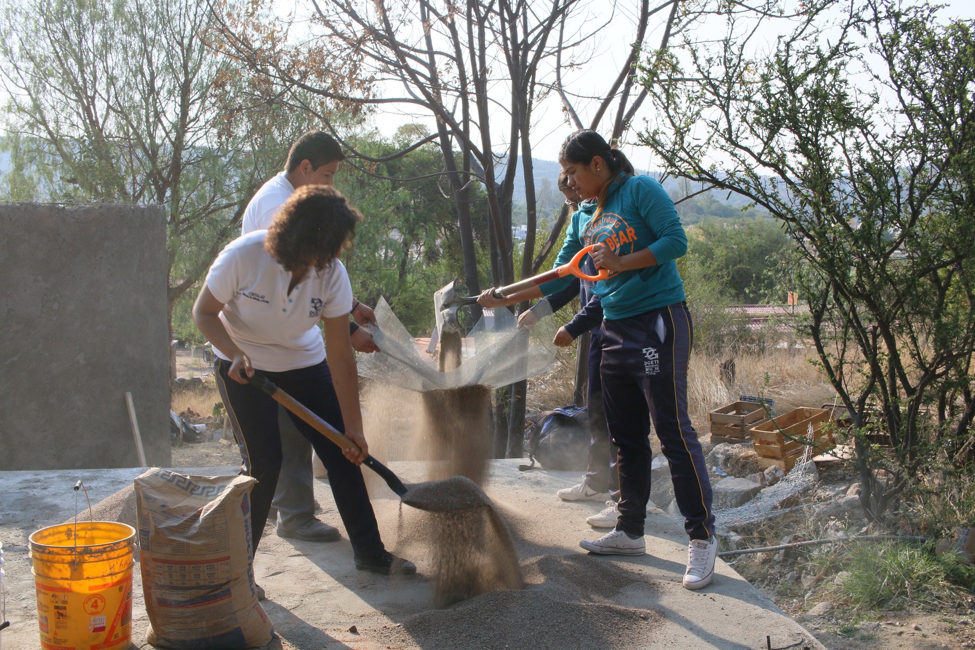 Los estudiantes criban la arena para la mezcla de cemento.