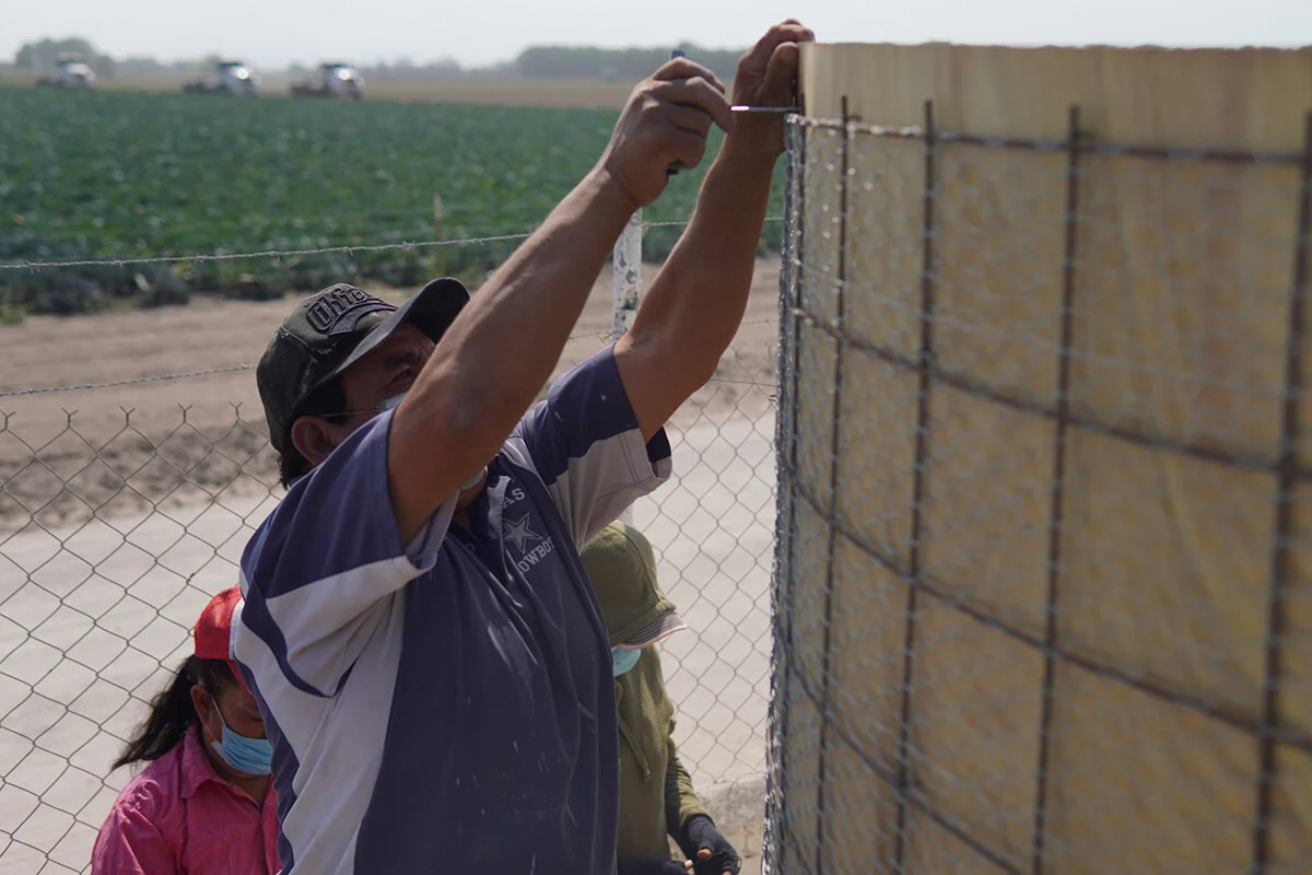 Photo: A community member building a Rainwater Harvesting System in the community of Jerico de María (in the background you can see an agricultural camp with modern irrigation systems).