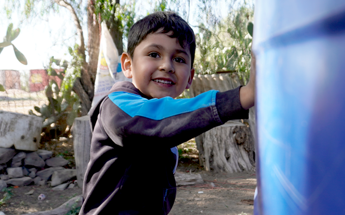Foto: Un pequeño niño, de la comunidad de Ejido de San Luis, jugando junto al sistema de cosecha de agua de lluvia de su familia.