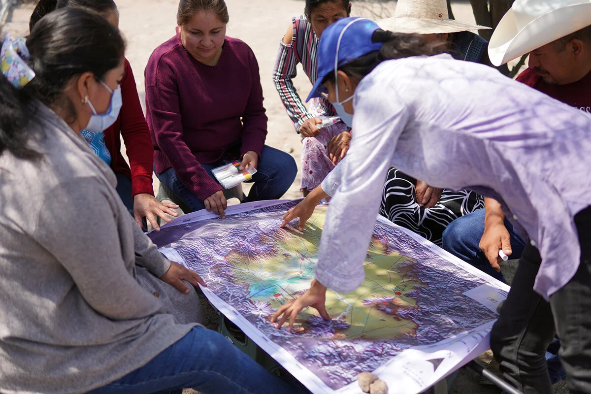 Photo: Ana Torres, Caminos de Agua's Community Organizer, at the community of Pozo Hondo showing a map of the Upper Rio Laja Watershed.