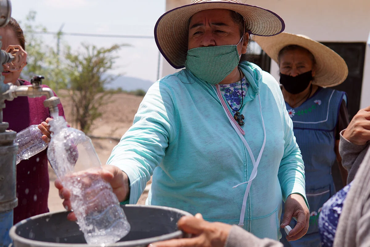 Photo: Lucha, long term collaborator of Caminos de Agua and community leader, taking a water sample from a well at the community of Misión de Chichimecas.