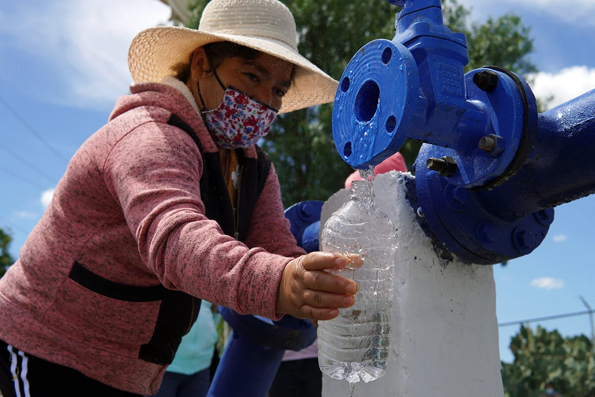 Foto: líder comunitaria tomando una muestra de agua del pozo comunitario.