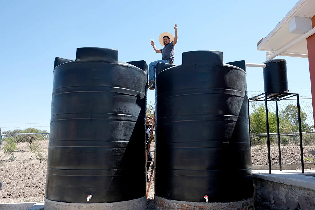 Foto: Saúl, Coordinador de Proyectos Comunitarios de Caminos celebra la construcción de un sistema de recolección de agua de lluvia de 20,000 litros (~5300 galones) en la primaria pública de la comunidad de Salitrillo.