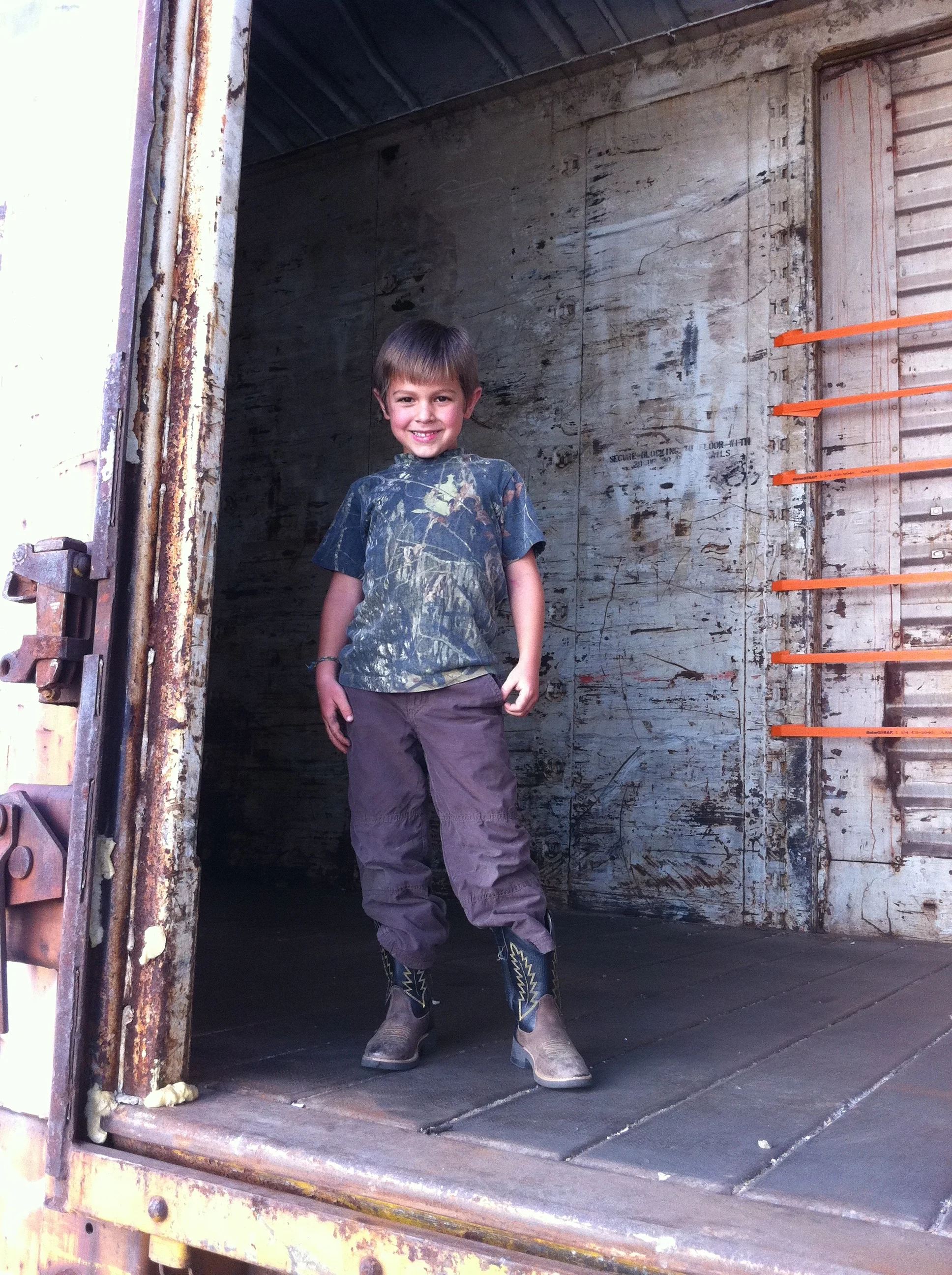 my son in an empty train car that is waiting to be loaded with cotton seed