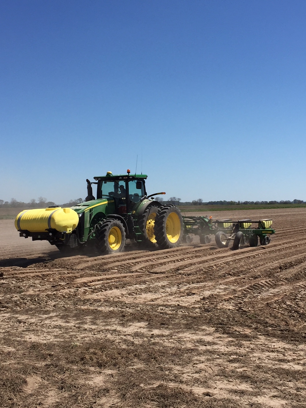 a tractor pulling a planter with cotton seed