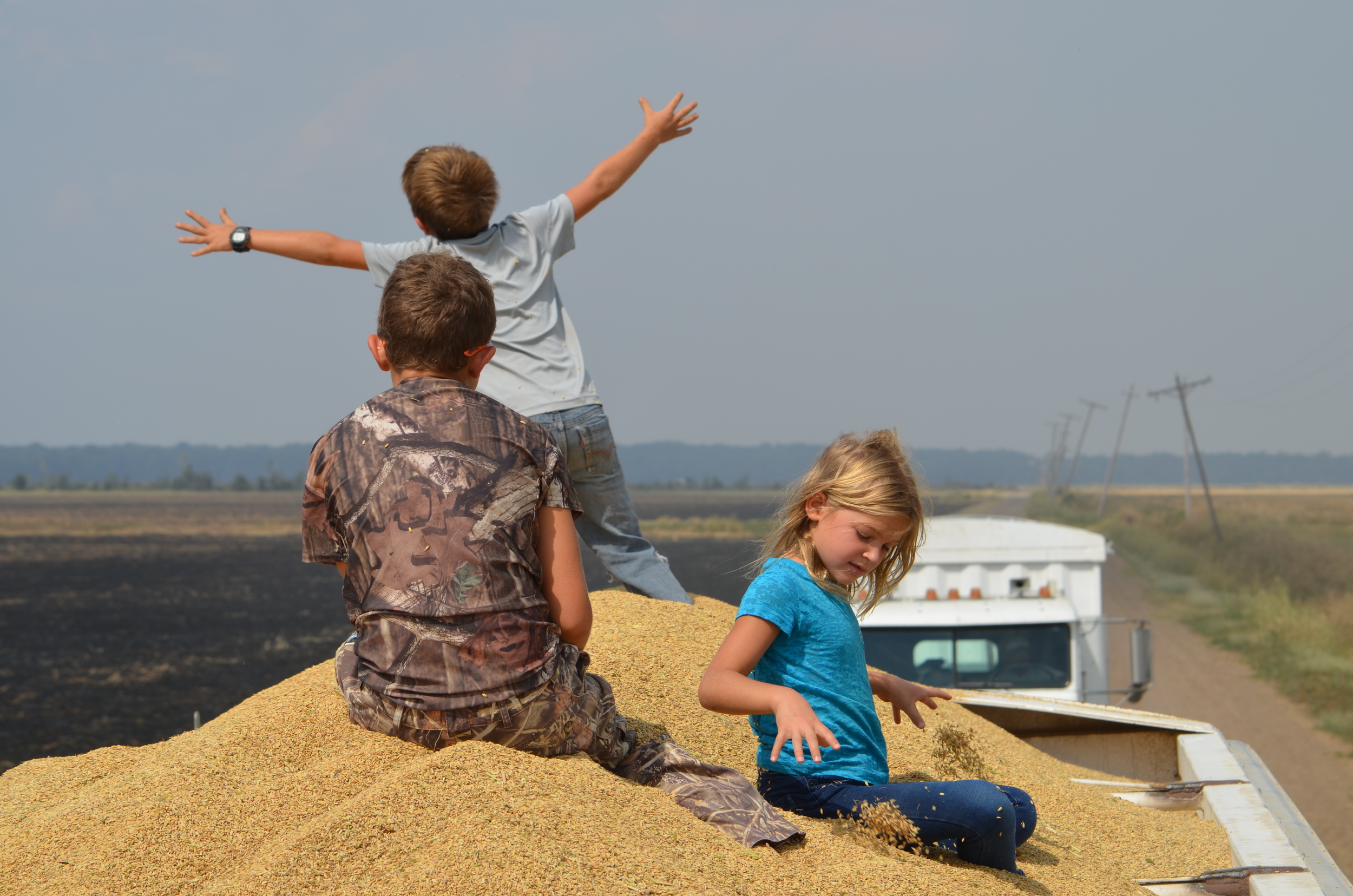 kids playing on a truck full of harvested rice