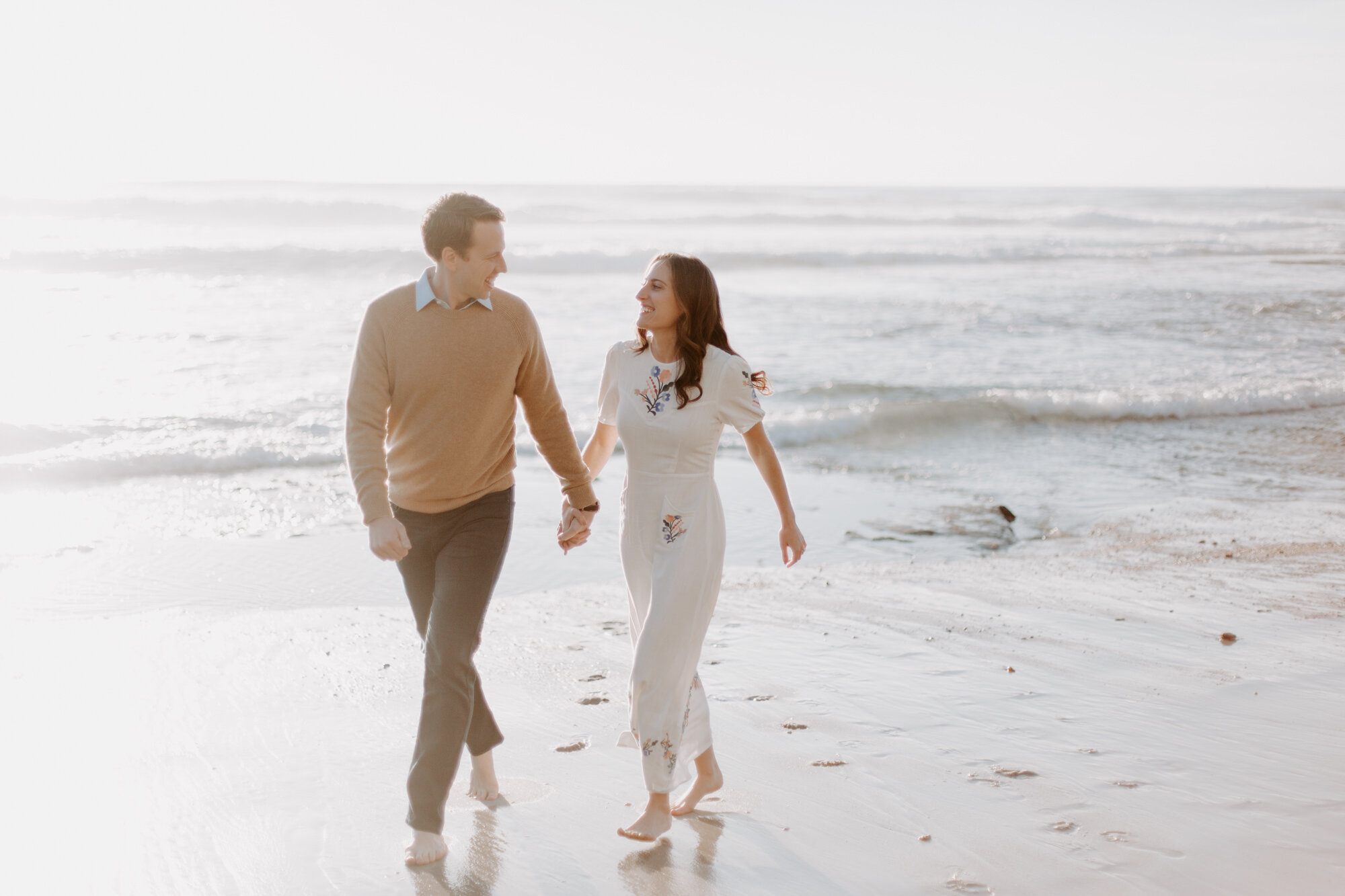 La Jolla Engagement Photos in San Diego with beach cliff and tide pools and on the sand.  Wore a white floral dress and took their engagement photos for their wedding by Kara Reynolds photography