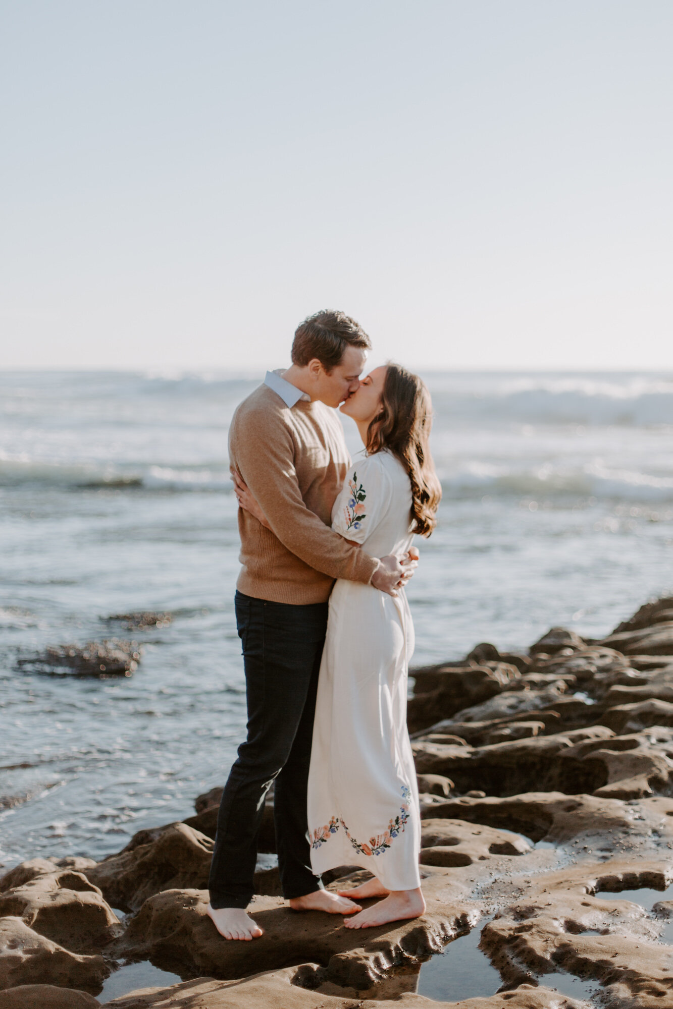 La Jolla Engagement Photos in San Diego with beach cliff and tide pools and on the sand.  Wore a white floral dress and took their engagement photos for their wedding by Kara Reynolds photography