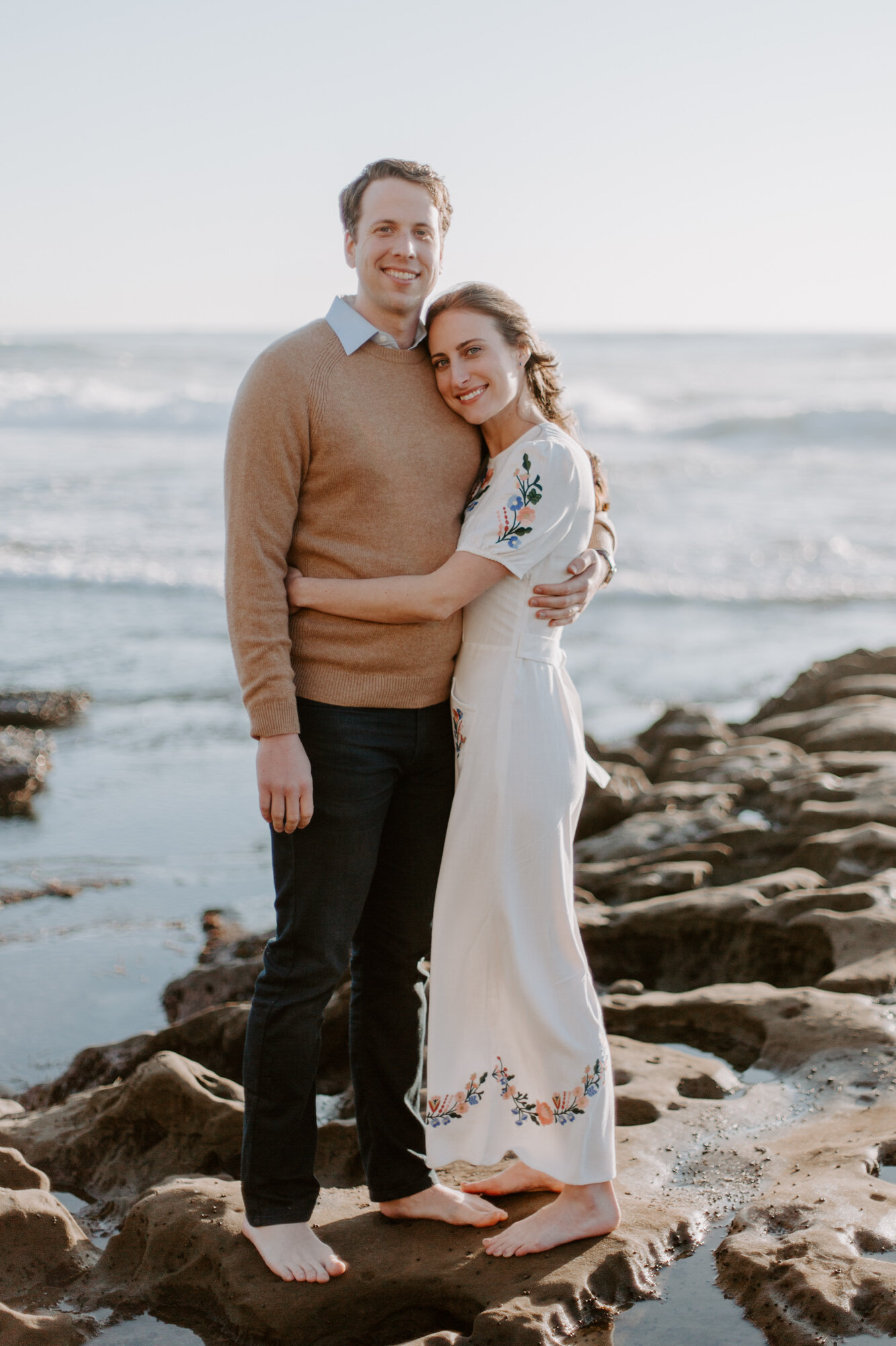 La Jolla Engagement Photos in San Diego with beach cliff and tide pools and on the sand.  Wore a white floral dress and took their engagement photos for their wedding by Kara Reynolds photography