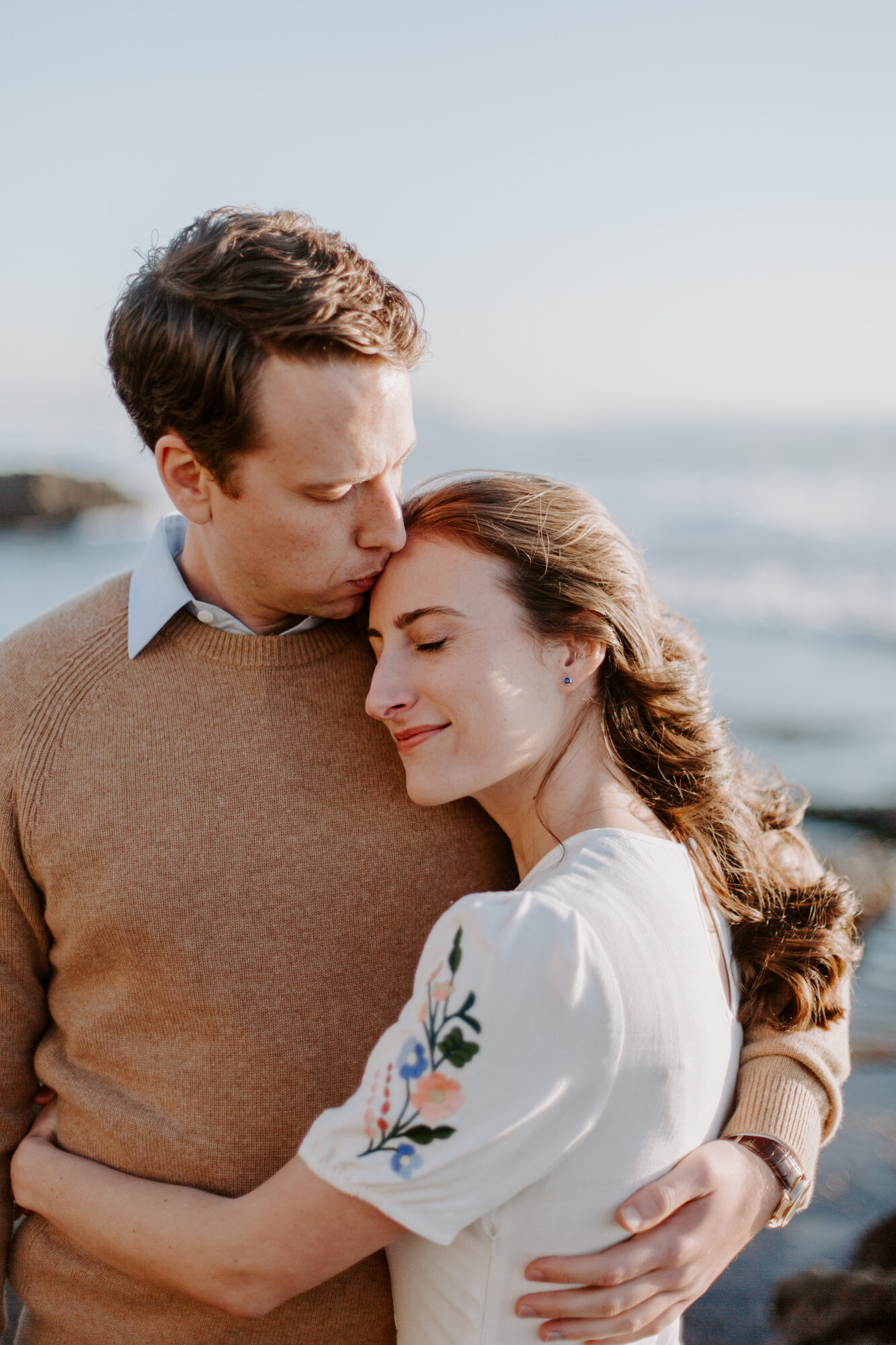 La Jolla Engagement Photos in San Diego with beach cliff and tide pools and on the sand.  Wore a white floral dress and took their engagement photos for their wedding by Kara Reynolds photography