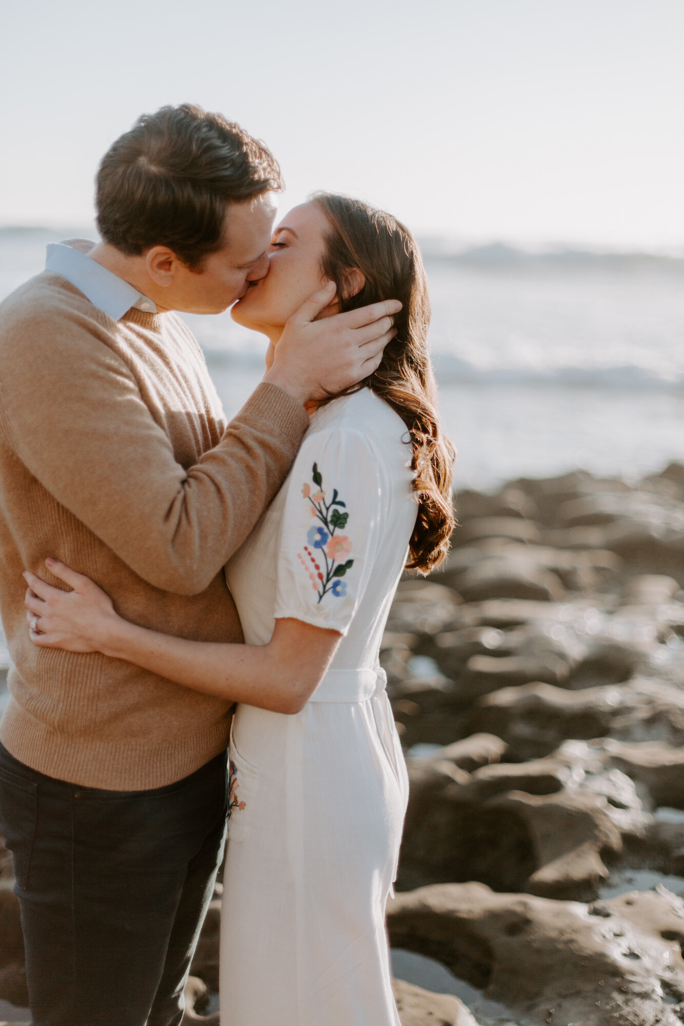 La Jolla Engagement Photos in San Diego with beach cliff and tide pools and on the sand.  Wore a white floral dress and took their engagement photos for their wedding by Kara Reynolds photography