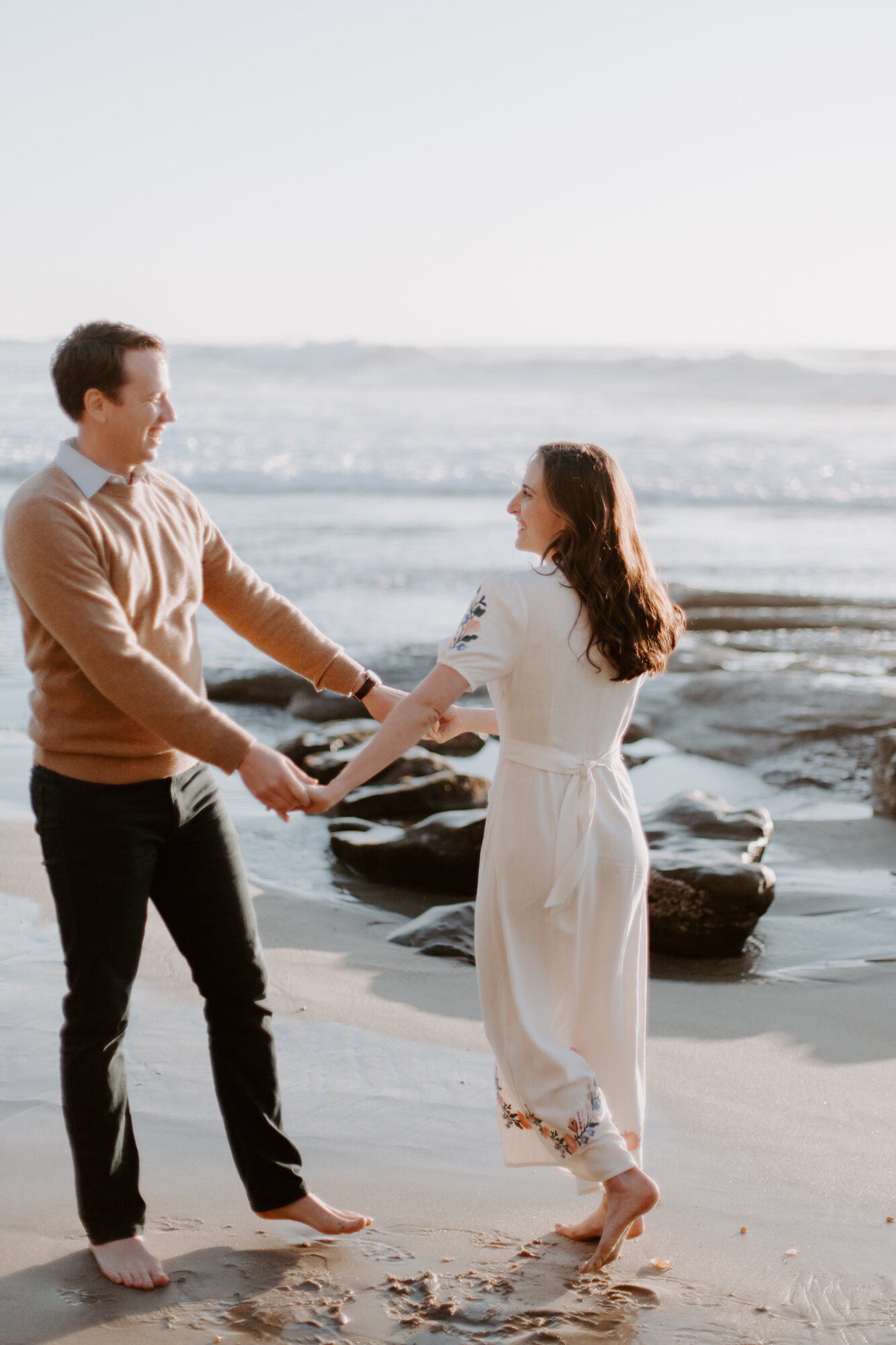 La Jolla Engagement Photos in San Diego with beach cliff and tide pools and on the sand.  Wore a white floral dress and took their engagement photos for their wedding by Kara Reynolds photography