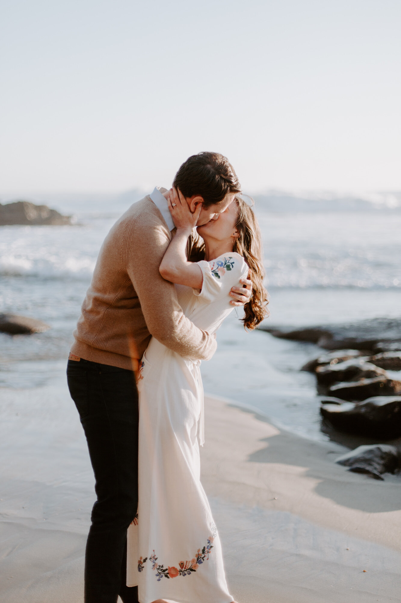 La Jolla Engagement Photos in San Diego with beach cliff and tide pools and on the sand.  Wore a white floral dress and took their engagement photos for their wedding by Kara Reynolds photography