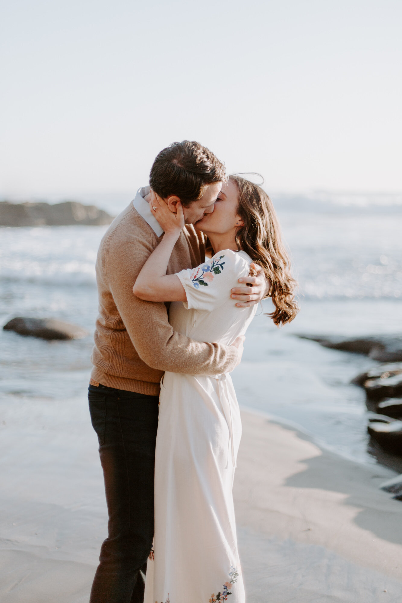 La Jolla Engagement Photos in San Diego with beach cliff and tide pools and on the sand.  Wore a white floral dress and took their engagement photos for their wedding by Kara Reynolds photography