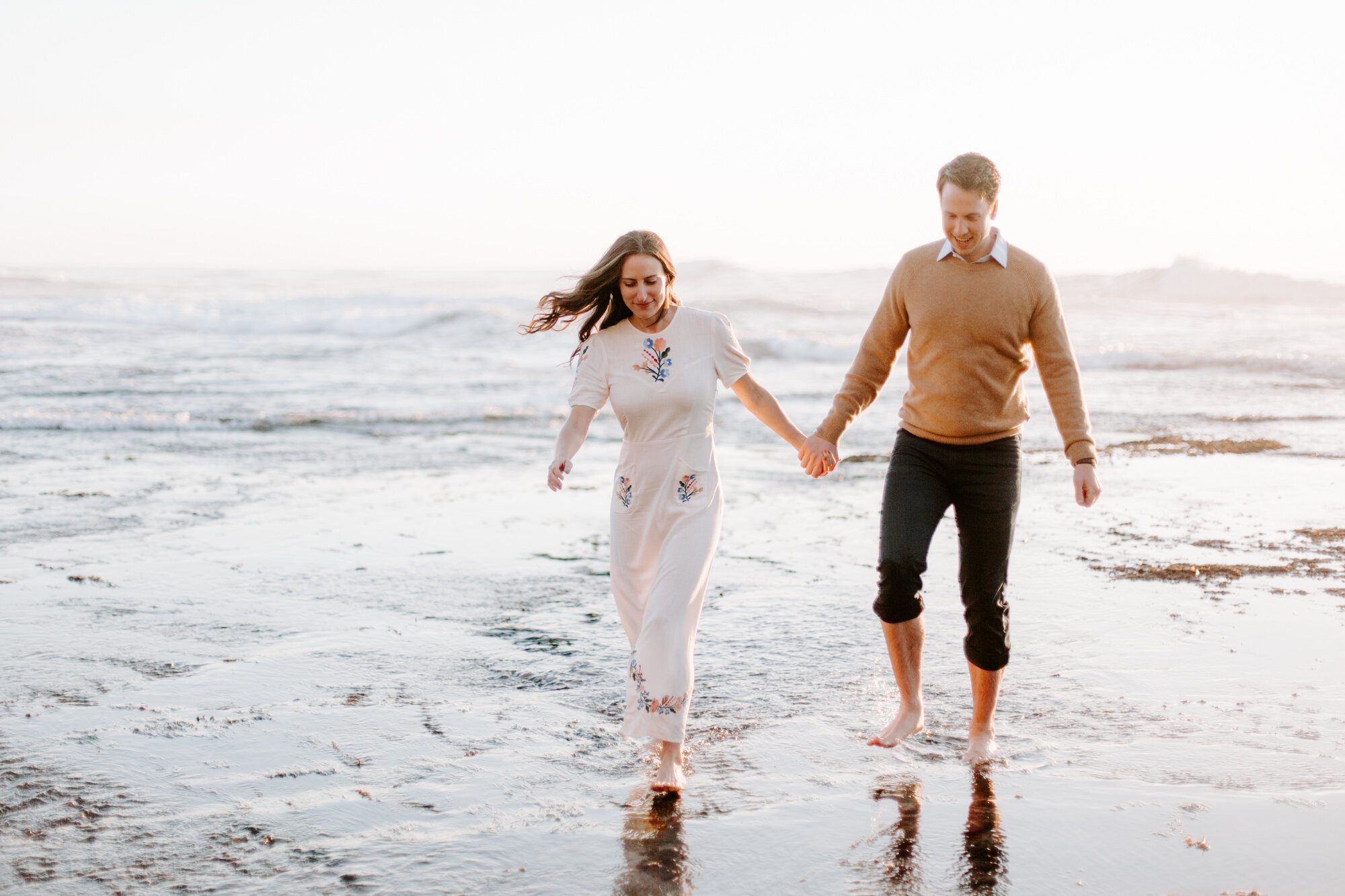 La Jolla Engagement Photos in San Diego with beach cliff and tide pools and on the sand.  Wore a white floral dress and took their engagement photos for their wedding by Kara Reynolds photography