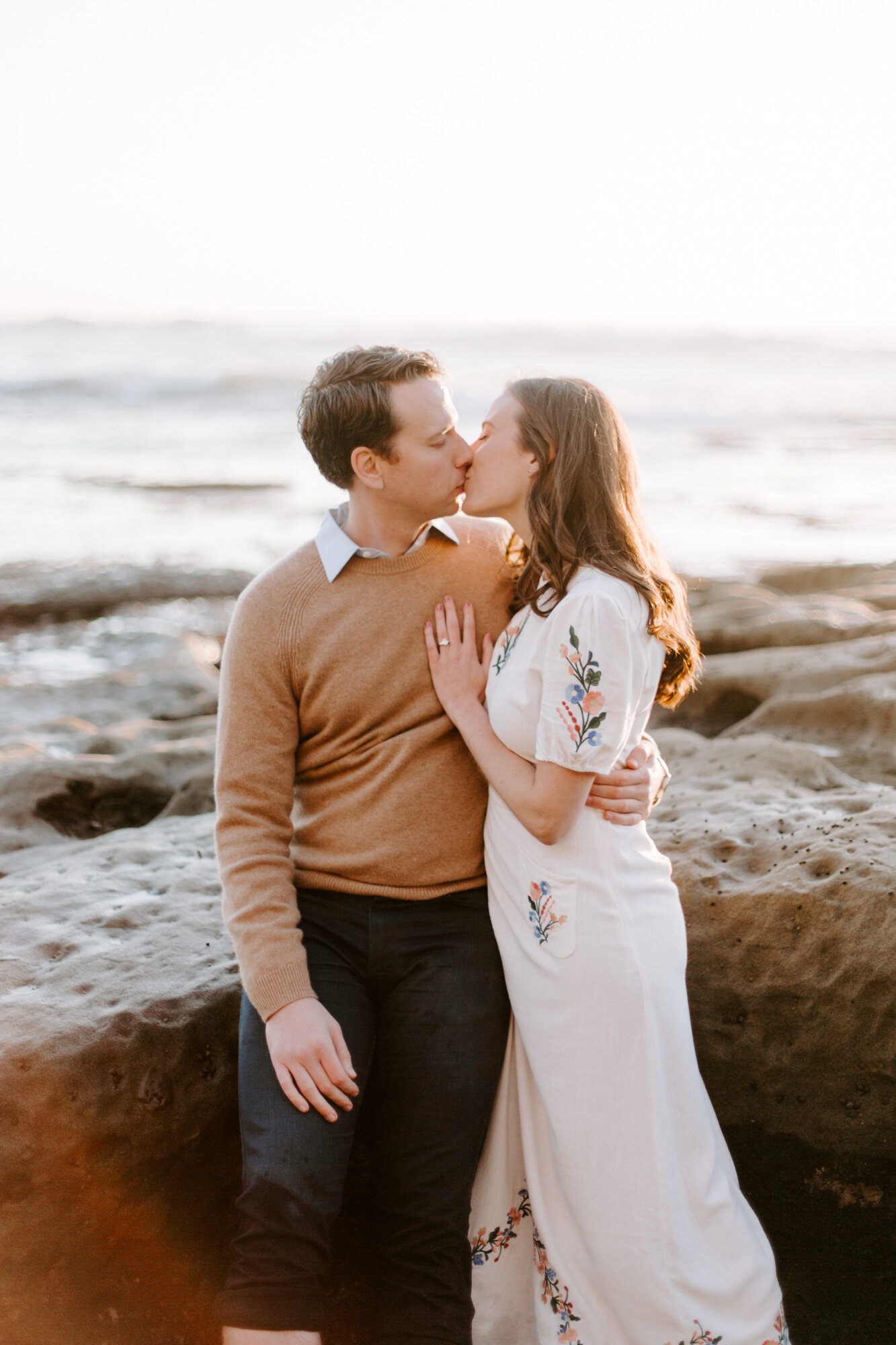 La Jolla Engagement Photos in San Diego with beach cliff and tide pools and on the sand.  Wore a white floral dress and took their engagement photos for their wedding by Kara Reynolds photography