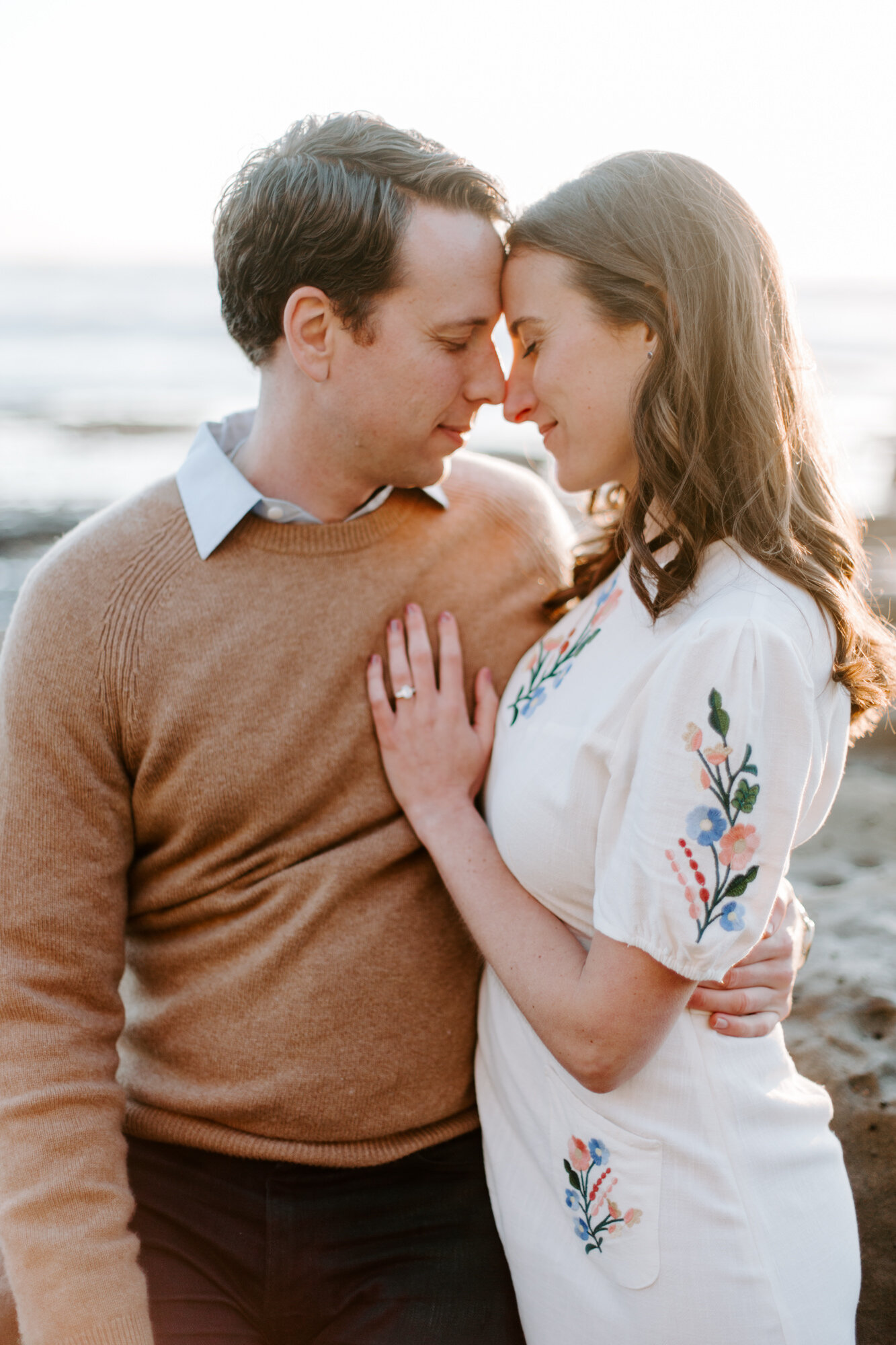 La Jolla Engagement Photos in San Diego with beach cliff and tide pools and on the sand.  Wore a white floral dress and took their engagement photos for their wedding by Kara Reynolds photography