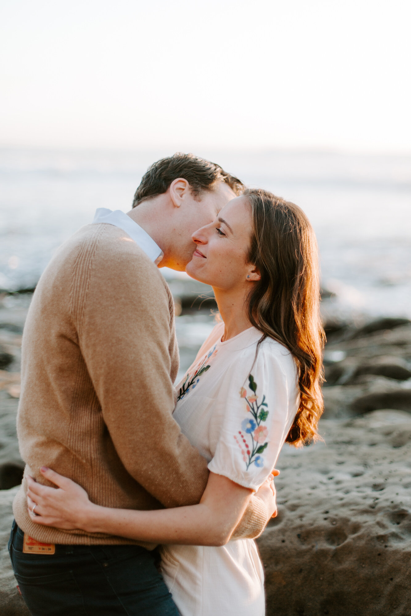 La Jolla Engagement Photos in San Diego with beach cliff and tide pools and on the sand.  Wore a white floral dress and took their engagement photos for their wedding by Kara Reynolds photography