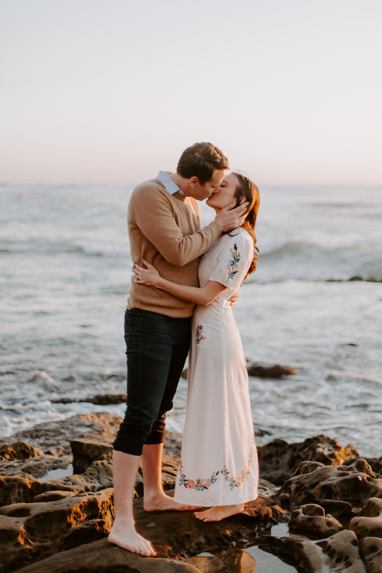 La Jolla Engagement Photos in San Diego with beach cliff and tide pools and on the sand.  Wore a white floral dress and took their engagement photos for their wedding by Kara Reynolds photography