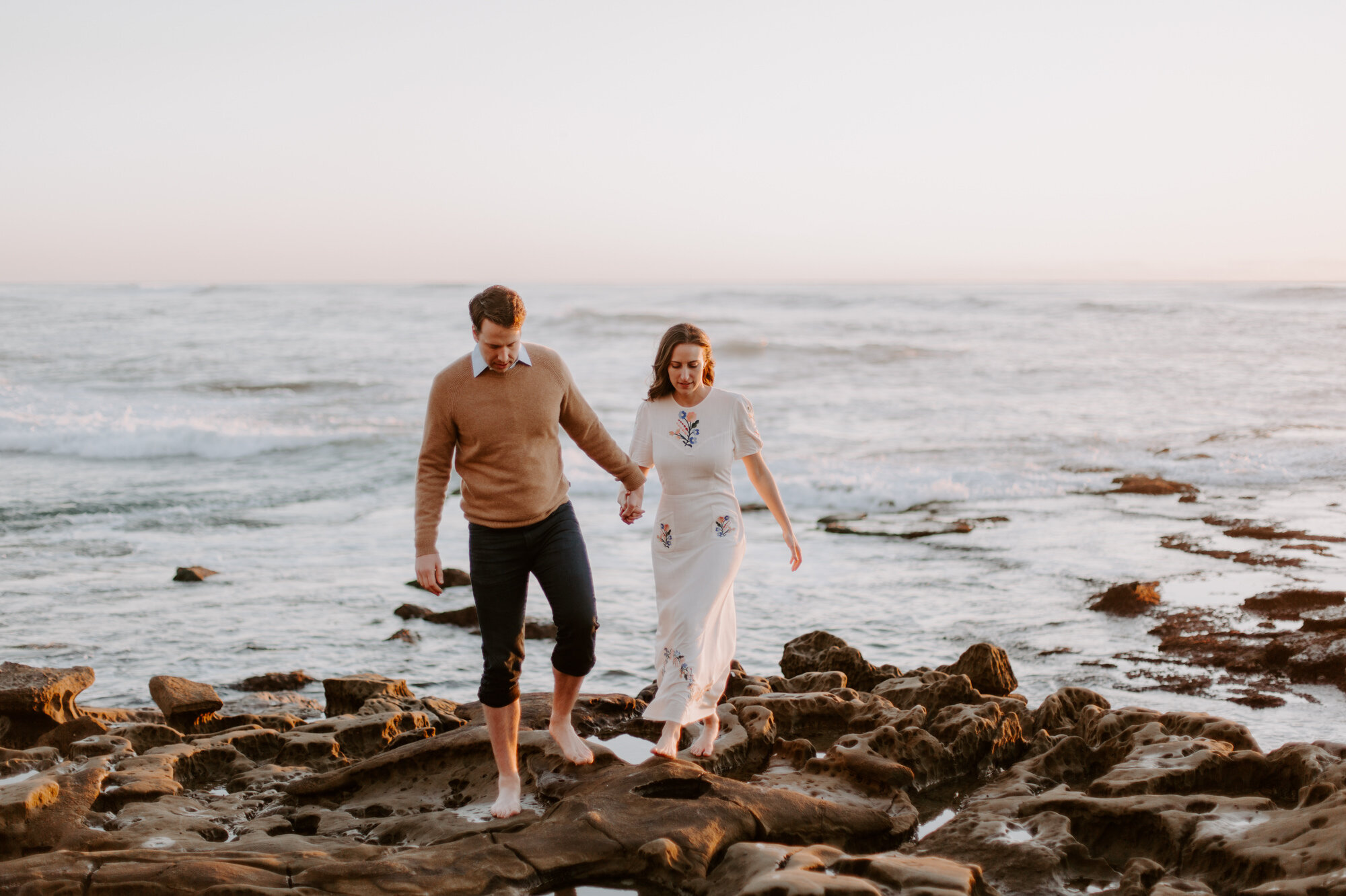 La Jolla Engagement Photos in San Diego with beach cliff and tide pools and on the sand.  Wore a white floral dress and took their engagement photos for their wedding by Kara Reynolds photography