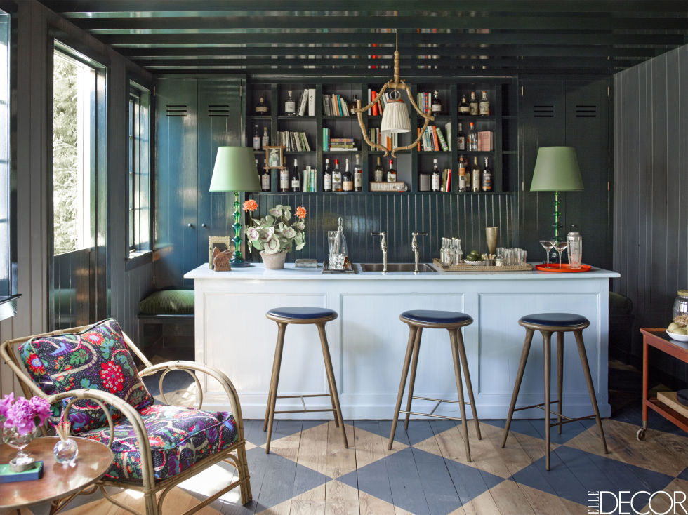 Contemporary Julian Chichester bar stools line a vintage bar, creating the perfect space for home entertaining. The cane armchair was found in a flea market and reupholstered in fabric by Austrian architect Josef Frank .