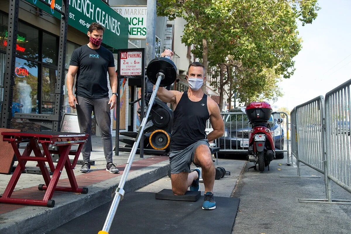 Shayne Jones works out under the supervision of trainer and co-owner Glenn Shope outside MX3 Fitness along Market Street in the Castro on Wednesday, July 29, 2020. (Kevin N. Hume/S.F. Examiner)
