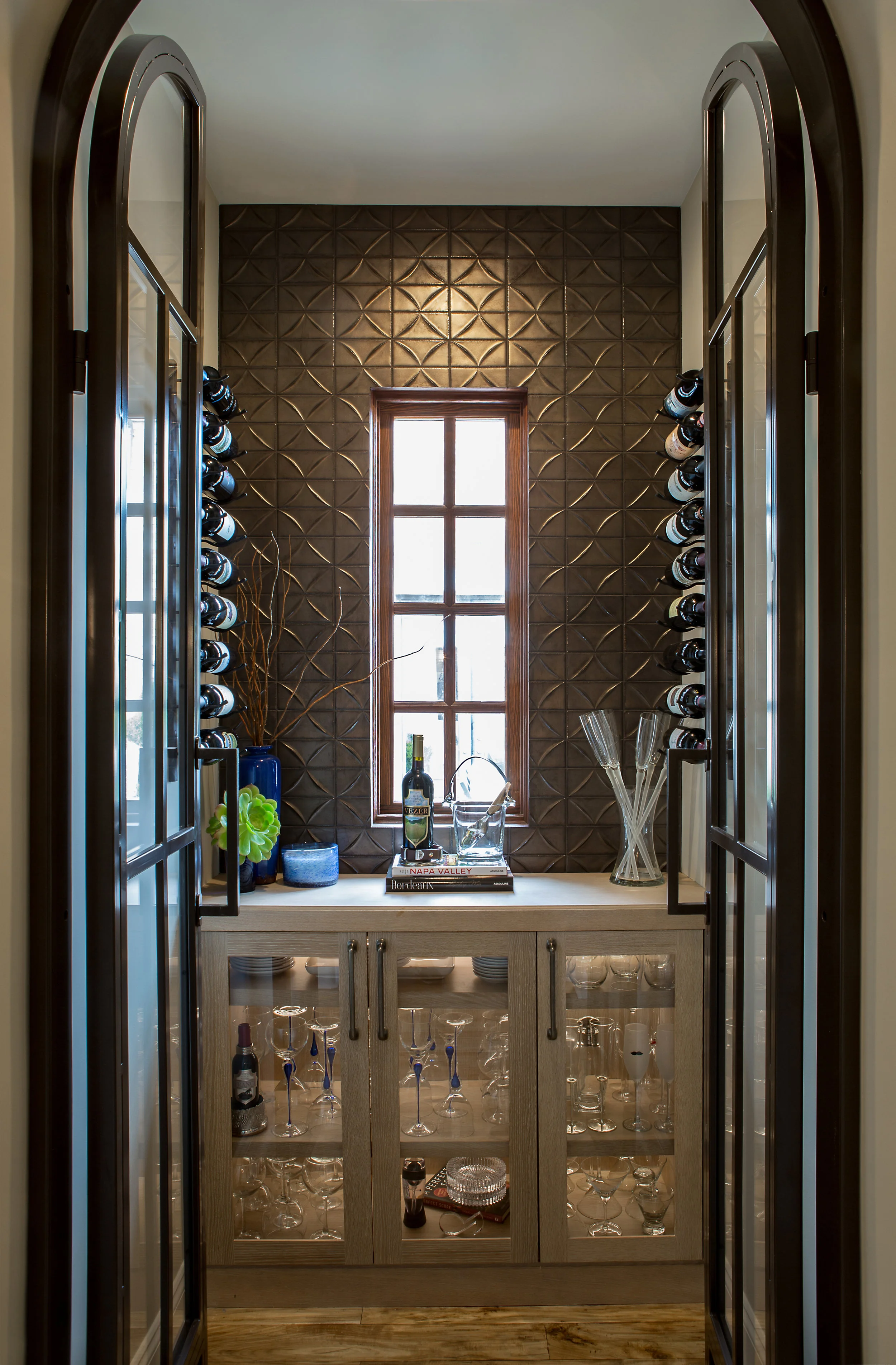 Small room reinvented. There was a small space next to the entry way that was not being used so we decided to create a wine room, more for a look or an experience that to be actually used for wine since we just installed a full height subzero wine cooler into the kitchen. The wine room as custom metallic tile that creates a mood flanked by custom iron doors to close off the small wine room.