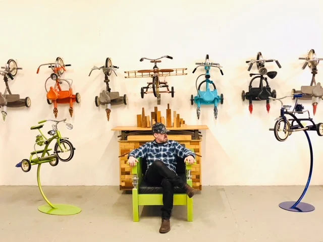 For two decades, Bradley Ehrsam has pioneered the art of transforming tricycles, reclaimed objects, motorcycle parts, and wood into exquisite sculpture, functional art, and paintings. Born in Chicago and raised in Wisconsin, where Harley Davidson was founded, Bradley surrounded himself with old school motorcycle culture and family friends that worked in the local factories. Bradley deconstructs tricycles, using them as a blank canvas to retell the stories of his adventurous childhood. His body of work symbolizes the creativity of a child, the memories of an adult, and is a vehicle to fuel one’s own imagination. With vivid chrome and vibrant color, precision of the blown glass, and ebullient wings and wheels, Bradley pushes the limits to assure that each trike, each sculpture, each painting, and each functional art piece inspires joy. Bradley fabricates his work with the combination of metal, wood, carbon fiber, and the incorporation of reclaimed objects including carbonators, gear shafts, and other unique artifacts. While receiving his Masters in Fine Arts and Public Practice from the Heron School of Art and Design, he combined his passion for art and design with his passion for empowering youth through the creative process. He expanded his work into a public practice forum connecting the community of youth in underserved schools, with the creation of public art. In 2012, Bradley and his wife co-founded BEME Creative, LLC that incorporates fine art, sculpture, custom furniture, and philanthropy. His non-profit organization, Art & Soul, was launched in 2016 to empower at-risk and handicapable youth through visual art. Bradley and his wife Mary live in the West Village in New York City. www.bradleyehrsam.com www.theartandsoul.org Instagram bradleyehrsam Instagram the_artandsoul 612-327-5758 ______________________________________________________________________________