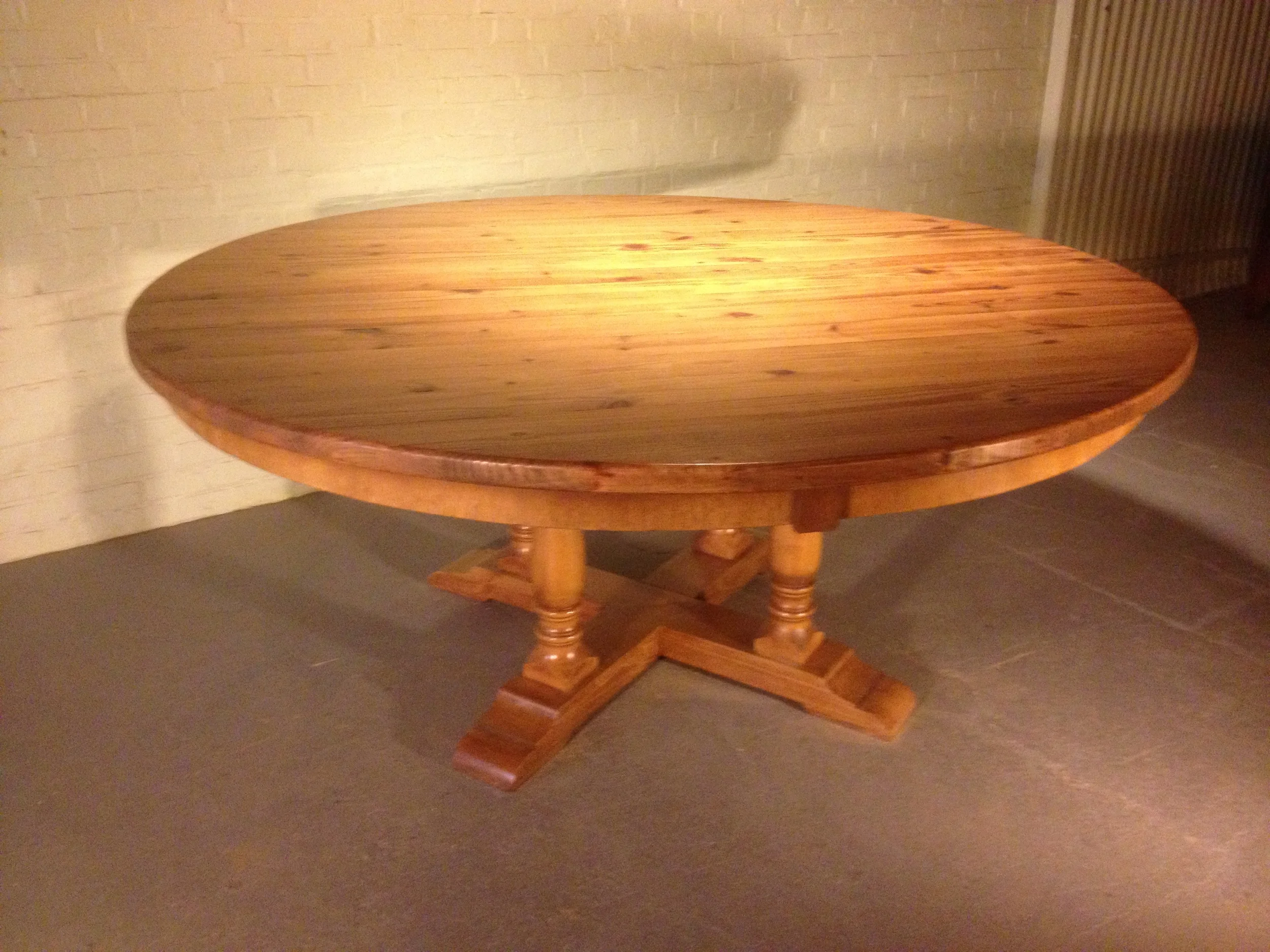 72" thick top round dining table with custom curved apron and Four Column pedestal finished in Golden Brown 