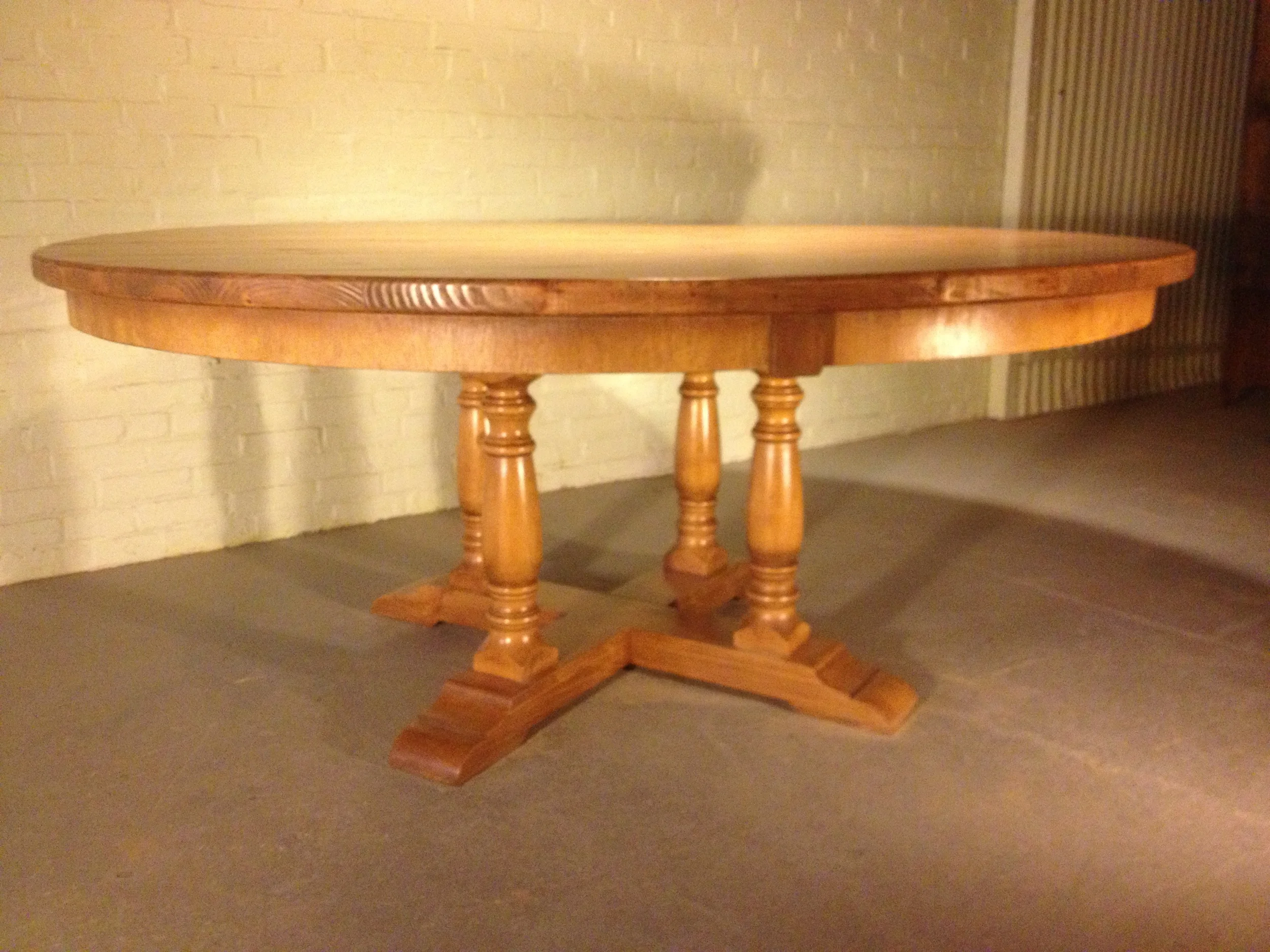 72" thick top round dining table with custom curved apron and Four Column pedestal finished in Golden Brown 