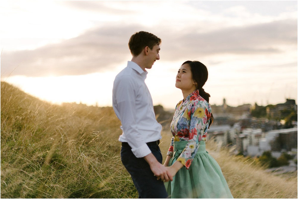  Korean Bride and British groom holding hands on top of Arthur seat in Edinburgh 