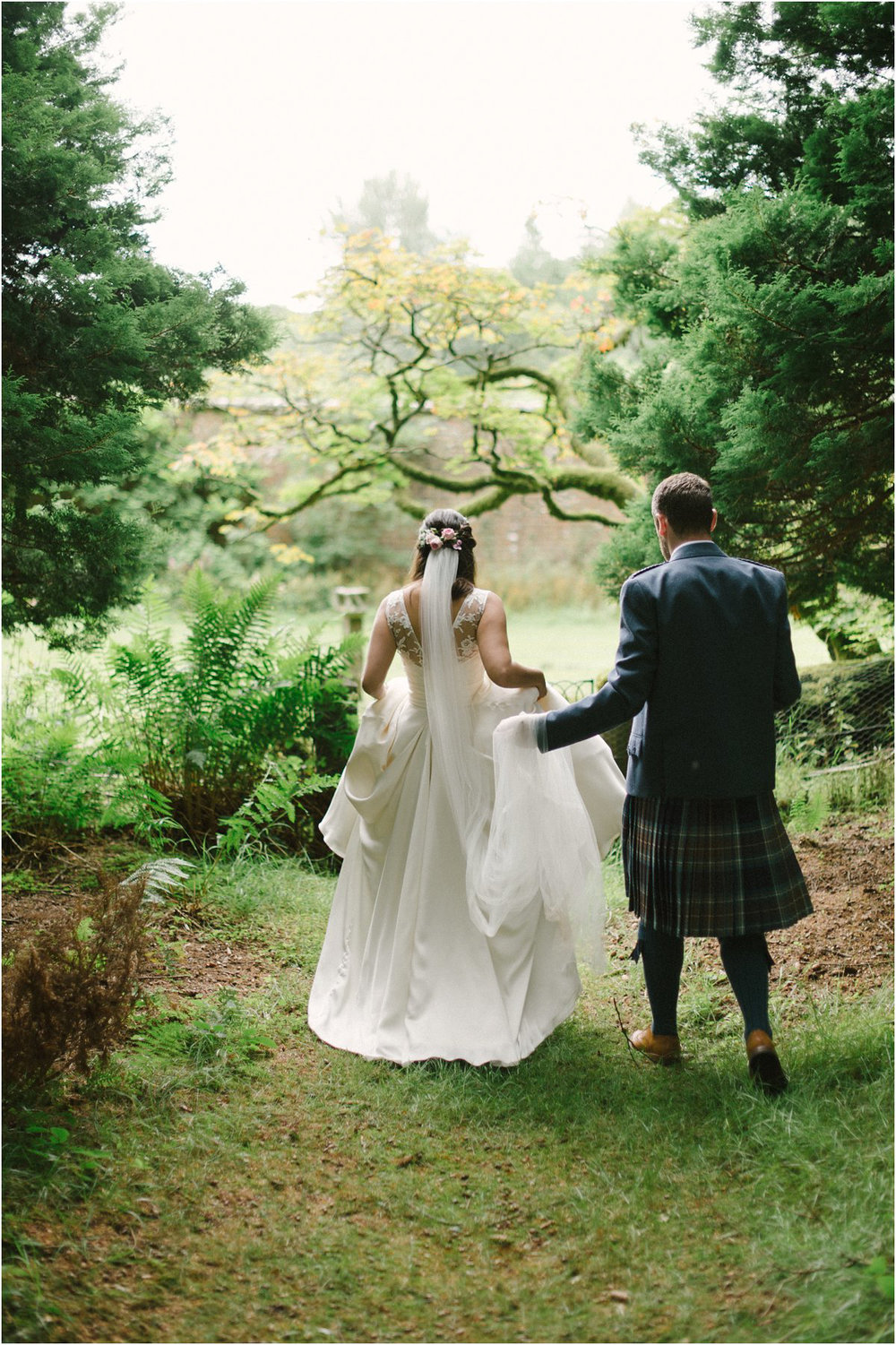  Bride and groom in kilt walking away in a forrest near Blairquhan castle in Scotland by Cro & Kow 
