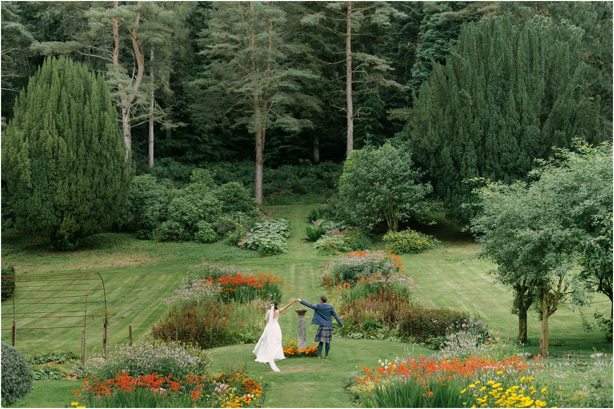  A wedding couple small in a frame when walking in a big garden of Blairquhan castle in Scotland by Cro & Kow 