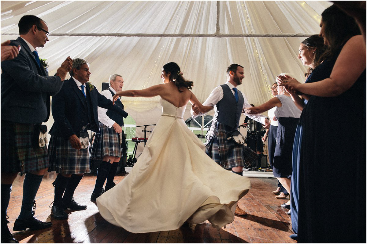 Bride in a big white dress swirling in a ceilidh during a summer Scottish castle wedding in Blairquhan by Cro & Kow 