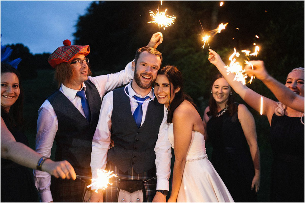  Bride and groom with their wedding party holding sparklers at dusk by Crofts & Kowalczyk Photography 