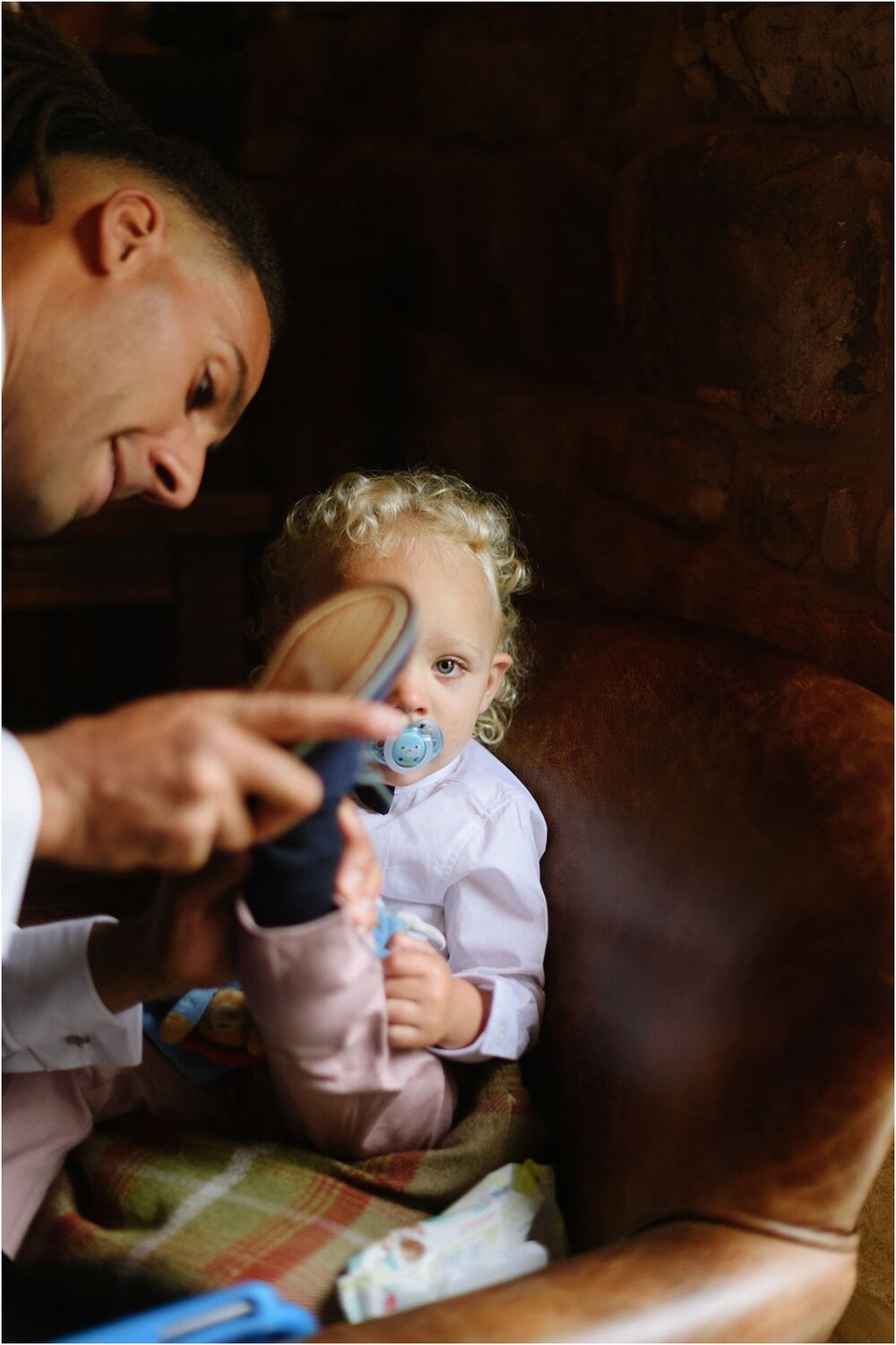  Father dressing his baby son for an English Countryside wedding at The Ashes Barns in Staffordshire with Classic white and green theme 