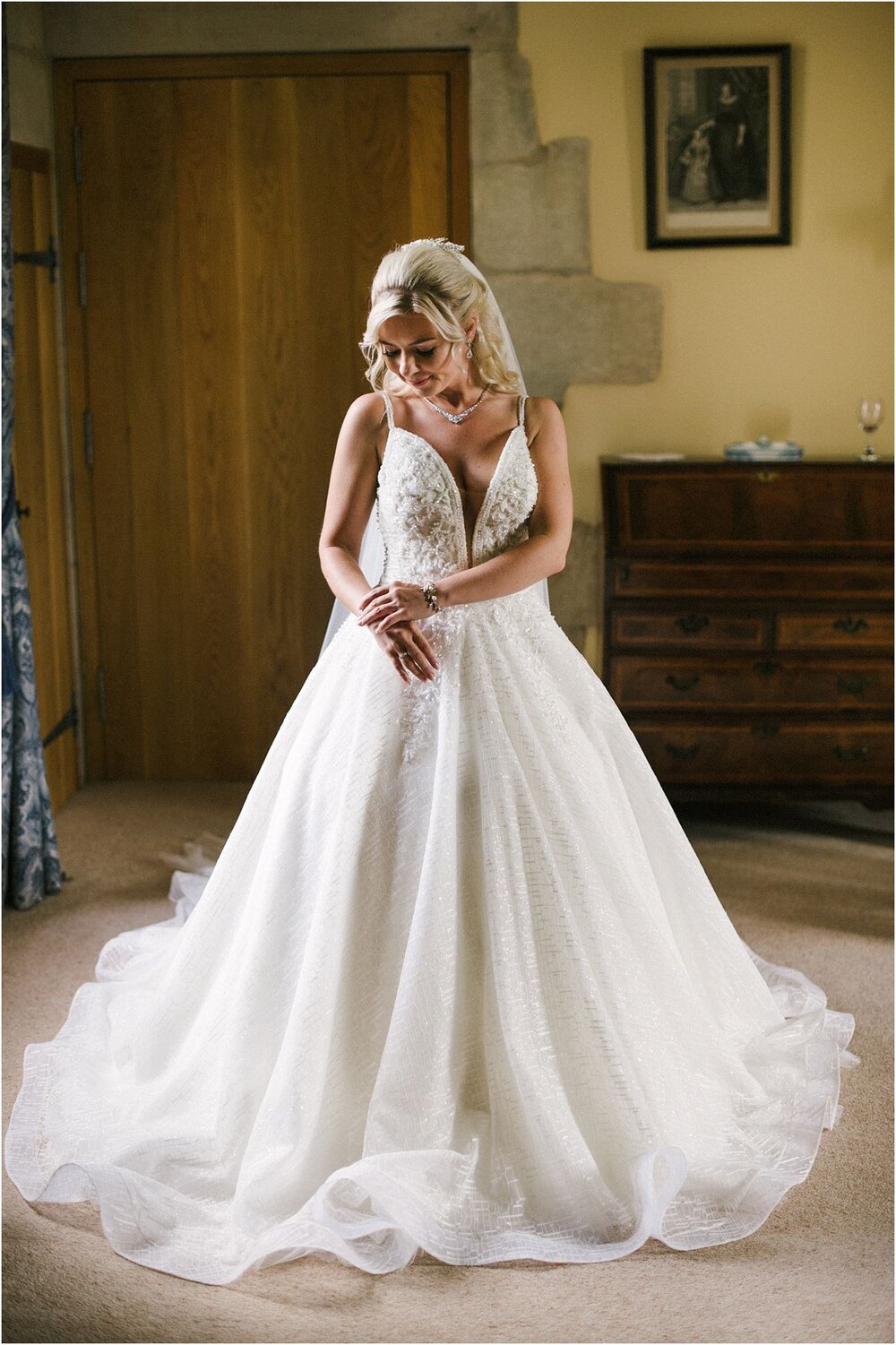  Portrait of a bride in her long white wedding dress and veil in a room in Winton Castle 