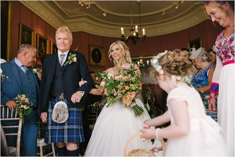  Bride entering the ceremony room with her dad walking her down the aisle at Winton castle  