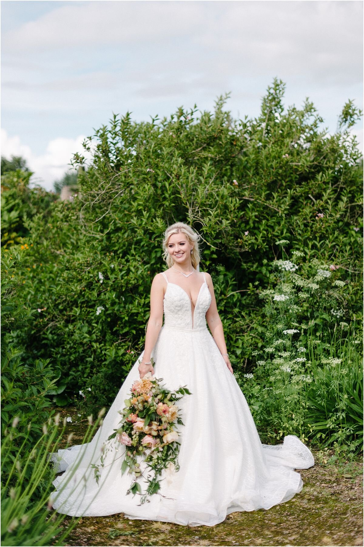  A portrait of a bride in a white dress during a Summer wedding at Winton castle Scotland with rustic flowers bouquet 