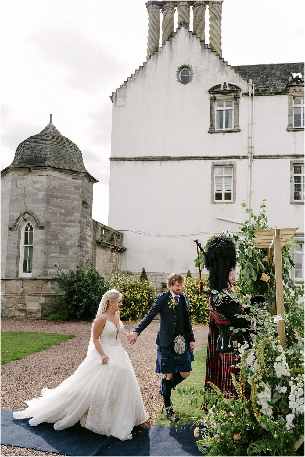  A young couple entering their wedding party at a summer wedding at Winton castle 
