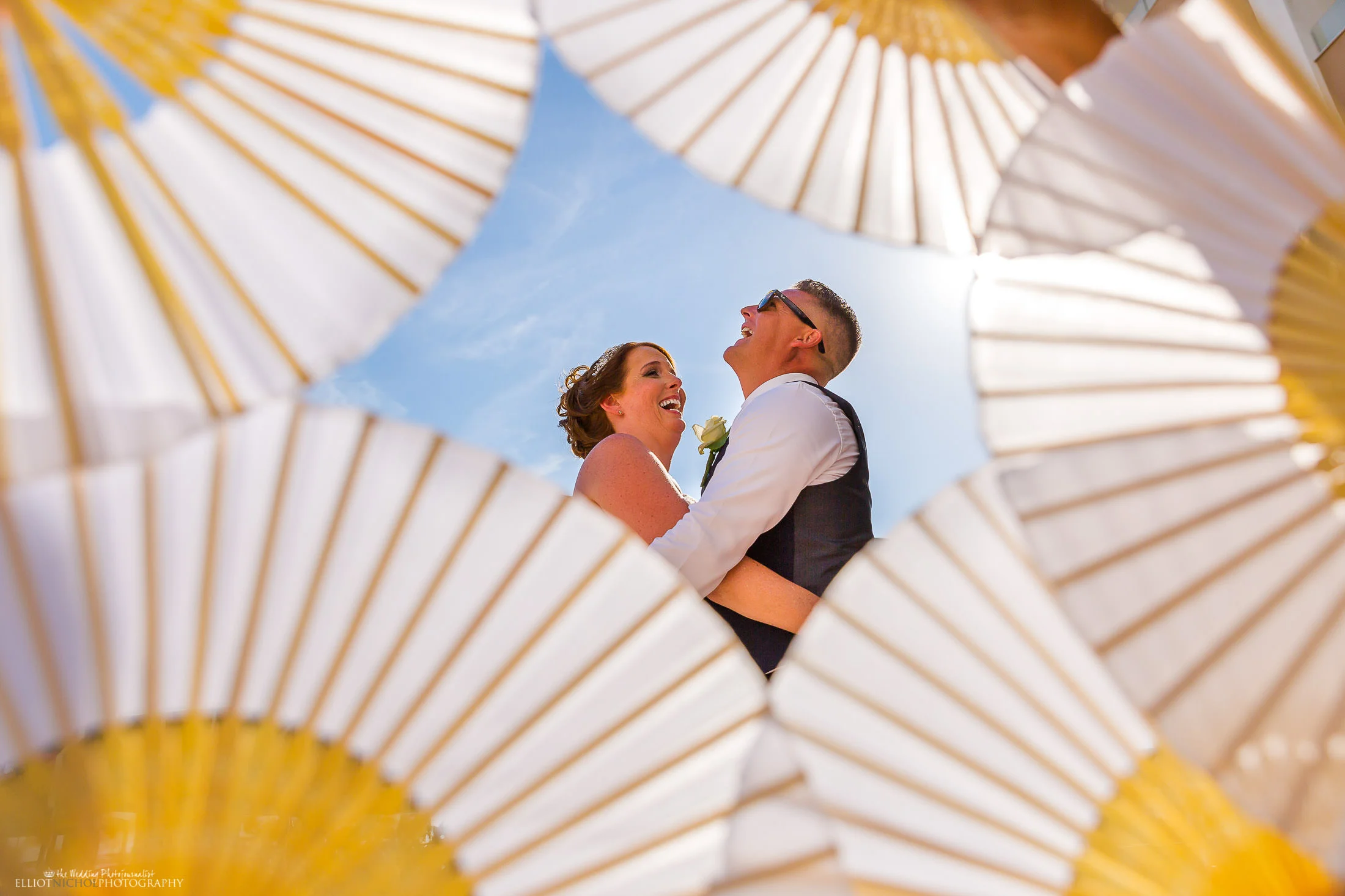 Fun creative portrait of the bride and groom using fans. Photo by Elliot Nichol Photography.