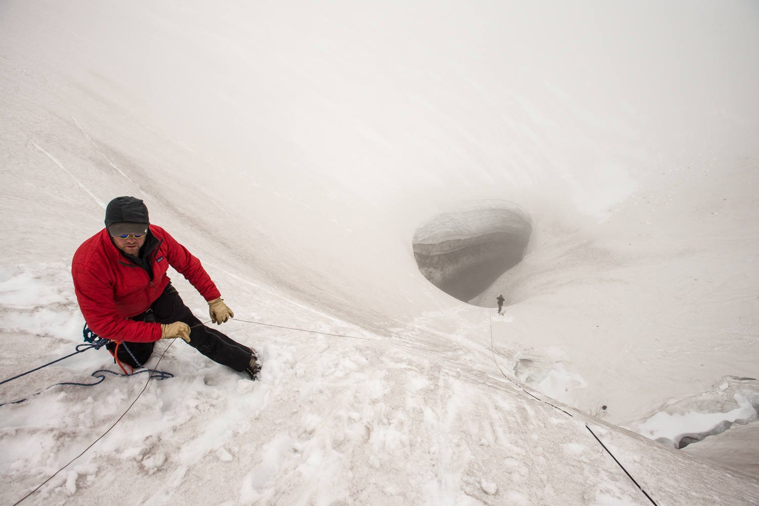 Craig McClure, logistics expert and owner of Crackerjack First Response Specialists, helps guide the phone line into Godzilla Hole on Mt St Helens. The team uses military 'cricket' phones (their ring sounds like a cricket) for surface to in-cave communications. Radios don't work in caves. 